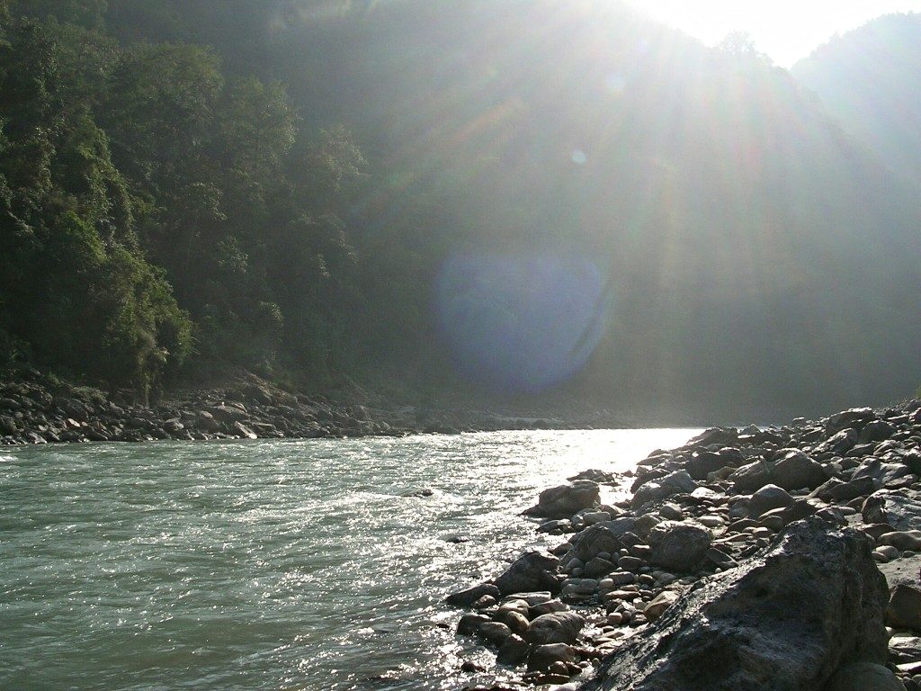 Die Sonne scheint auf den Fluss Kali Gandaki mit einem Ufer voller großer Steine