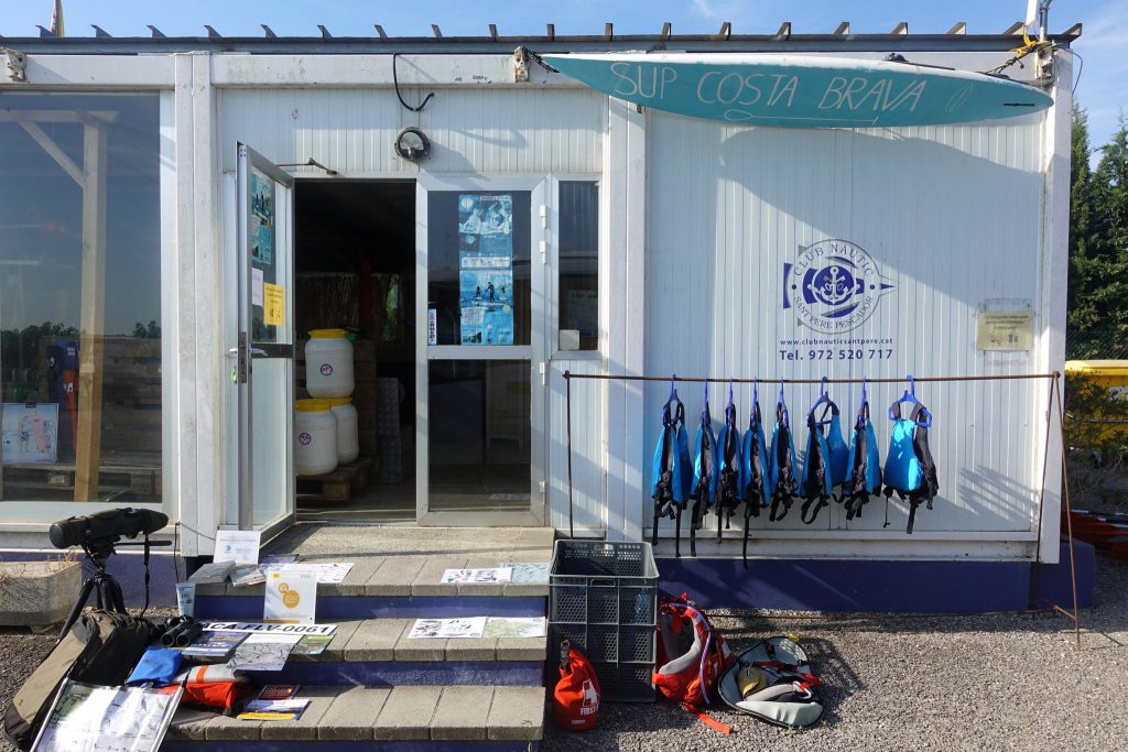 Containerhäuschen von Sk Kayak beim Club Nautic in Sant Pere Pescador mit Stufen; blauen Schwimmwesten hängen auf einer Stange