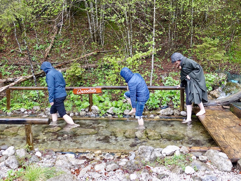 Drei Menschen gehen durch ein Wasserbecken